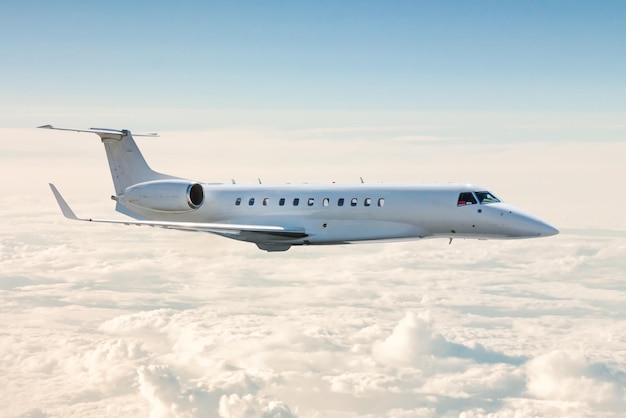 White business jet flies in the air above the clouds