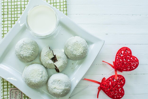 White cake with coconut flakes and a glass of milk top view