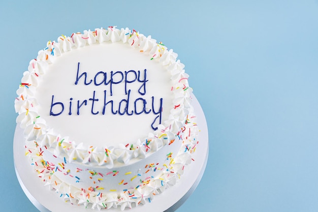 White cake with the inscription happy birthday on blue background top view