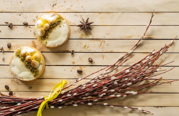 White cake on a wooden backgroundwillow branches and sweets top view