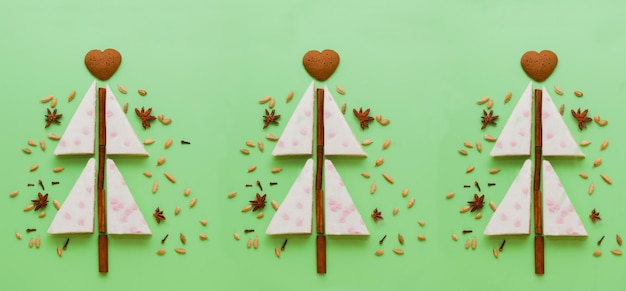 White cakes christmas tree shaped with Gingerbread cookies anise cinnamon pie flat lay on green