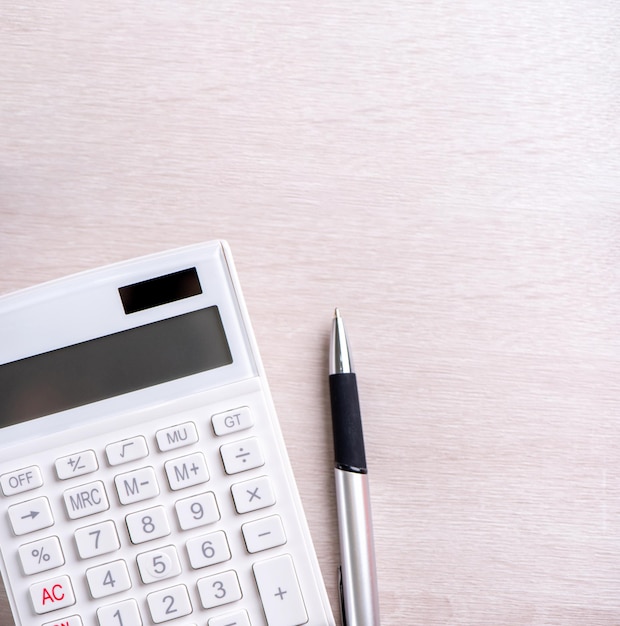 White calculator and pen on bright wooden table analytics and statistics of financial profit investment risk concept copy space top view flat lay