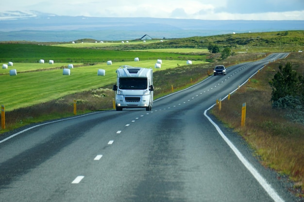 White camper driving on a road front view