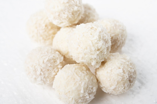 White candies with coconut, nuts and cream on a white background