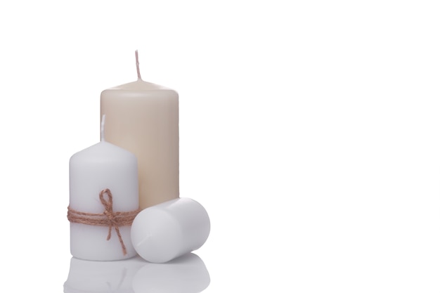 white candle in jute rope, white candle lying on its side and beige vanilla candle isolated