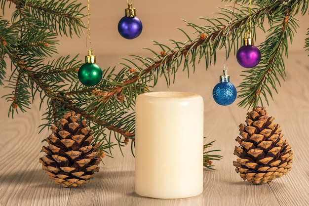 White candle and natural fir tree branches with Christmas ornament