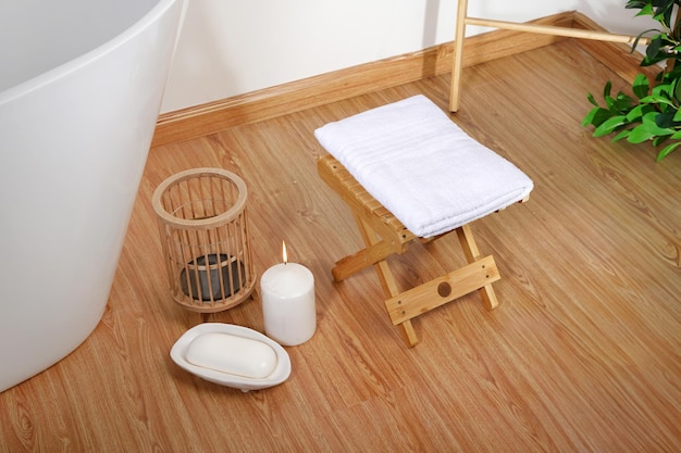 a white candle on a wooden floor with a white candle in it towels on wooden in bathroom decor and Sp