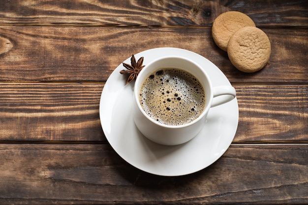 A white cap of coffee and anise on a small plate with two cakes