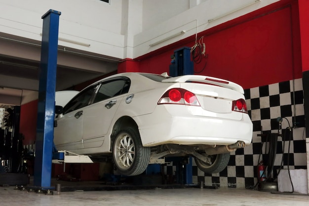  a white car is lifted up for the repairing process