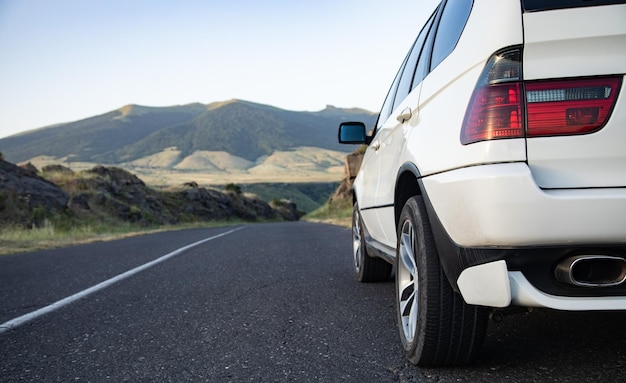 White car moves on the road among the mountains