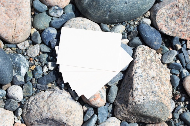 A white card is laying on a pile of rocks on the beach.