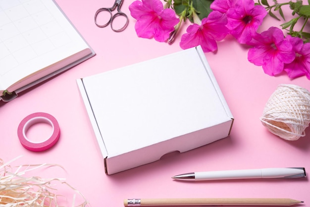 White cardboard carton box on pink background decorated with red flowers