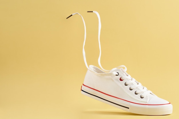 White casual sneakers on yellow background creative minimalism