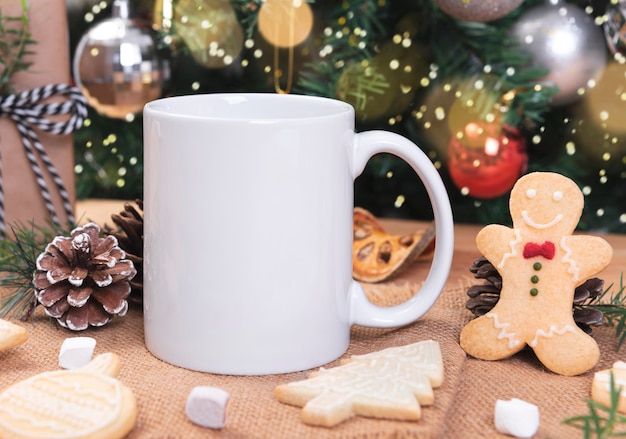 White ceramic coffee cup and christmas decoration on woon table background. mockup for creative advertising text message or promotional content.