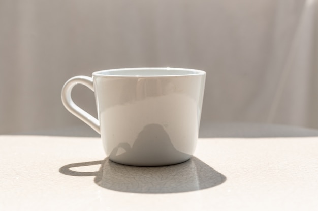 White ceramic coffee cup on white ceramic table on sunny day