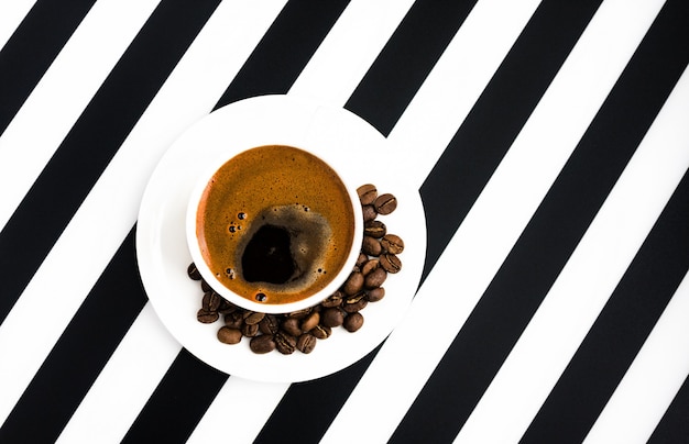 White ceramic cup of strong coffee on striped background