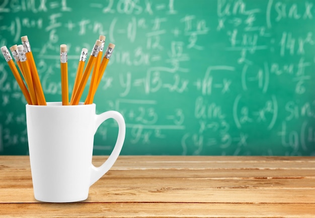 White ceramic cup with pencils on background