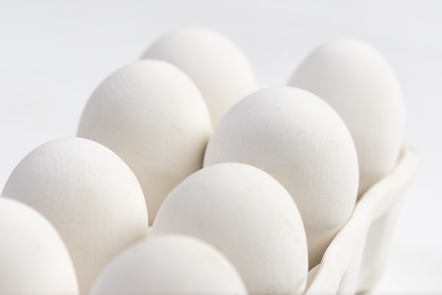 White ceramic eggs on a box with white background. Macro photo. Food concept.