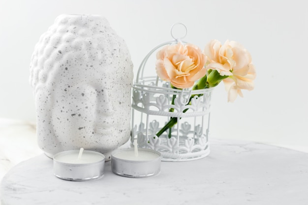 Photo white ceramic figurine buddha head  ,decorative cage with flowers and candles