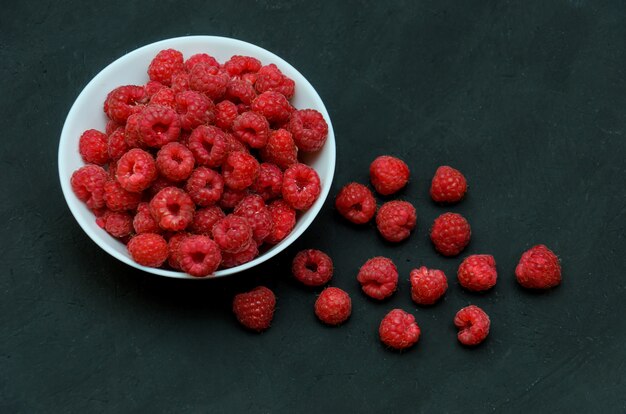 White ceramic plate full of juicy ripe raspberries