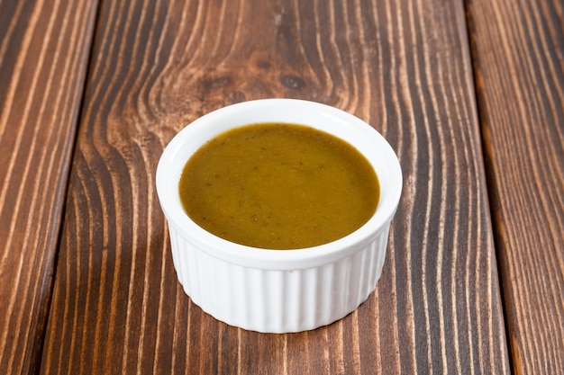 White ceramic sauce-boat of georgian sauce green tkemali on wooden table