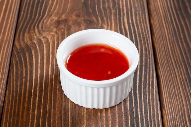 White ceramic sauce-boat of red sweet and sour sauce