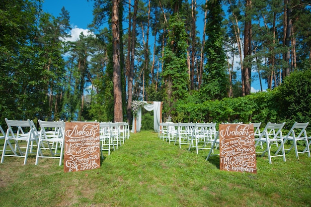 White chairs and wedding arch for the ceremony in the woods