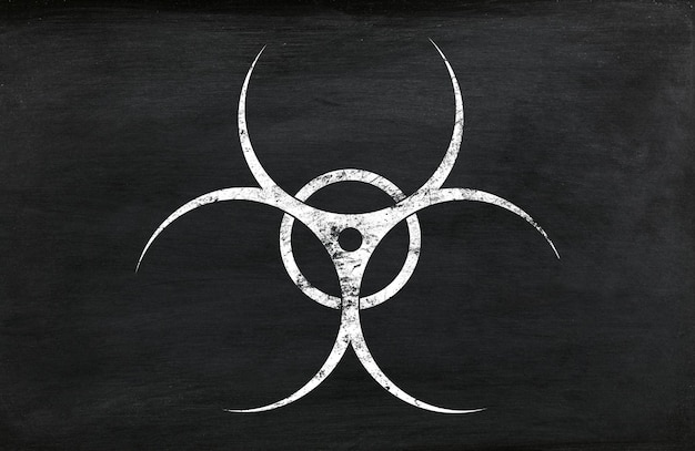 White chalk biohazard warning sign painted over grunge black chalkboard background with copy space