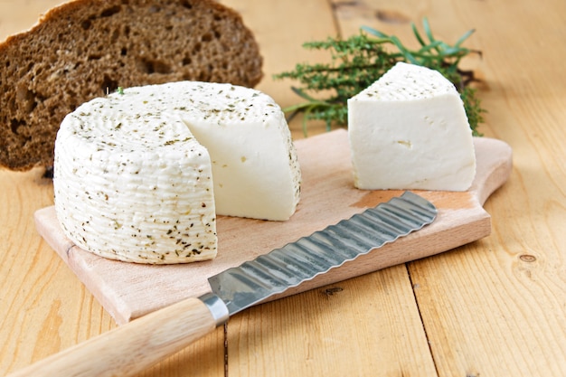 White cheese and bread on a wooden background and greens