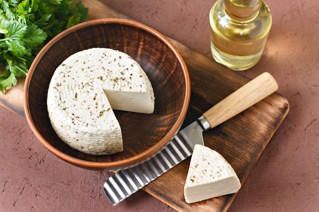 White cheese on a wooden board with olive oil on a brown background