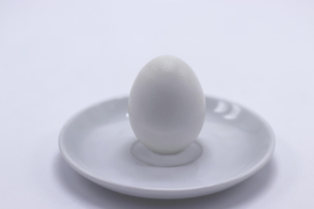 White chicken egg on a saucer closeup White background Minimalism