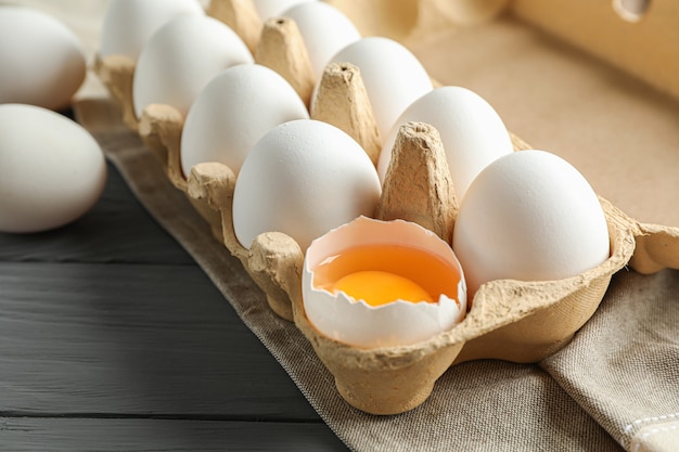 White chicken eggs in carton box on wooden table