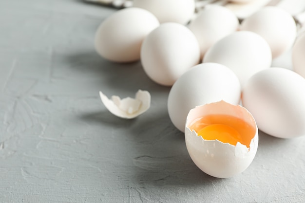 White chicken eggs and kitchen towel on grey