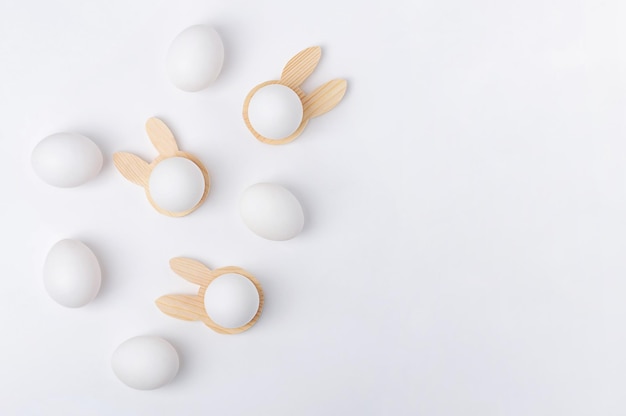 White chicken eggs on a stand in the form of a rabbit on a light background