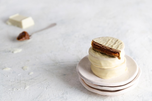 White chocolate alfajores, a piece of chocolate and a spoonful of dulce de leche.