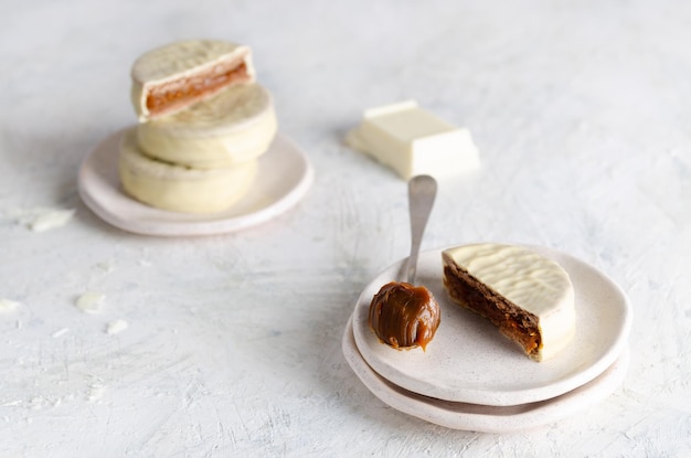 White chocolate alfajores, a piece of chocolate and a spoonful of dulce de leche.