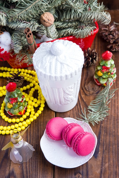 White christmas cup and pink macaroons on wooden background