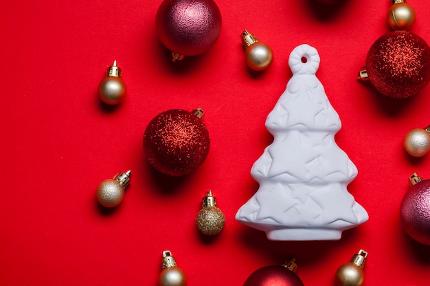 White Christmas tree and festive bauble decorations on a red background