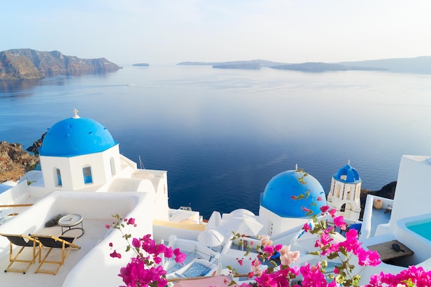 White church belfry blue domes and volcano caldera with sea landscape beautiful details of Santorini island with flowers Greece