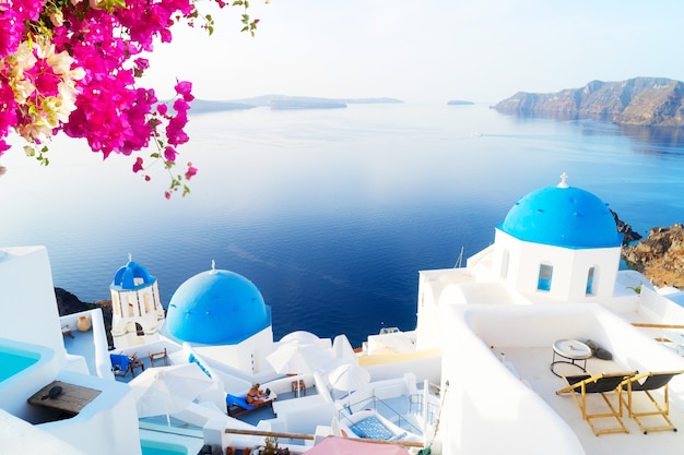 White church belfry, blue domes and volcano caldera with sea landscape