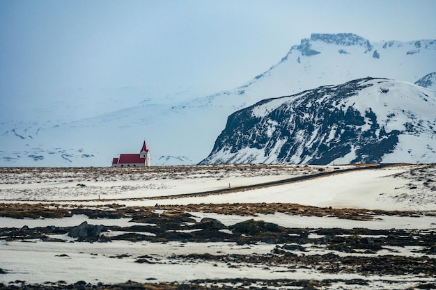 White church with red roof in the snowy landscape of Hellisandur Iceland