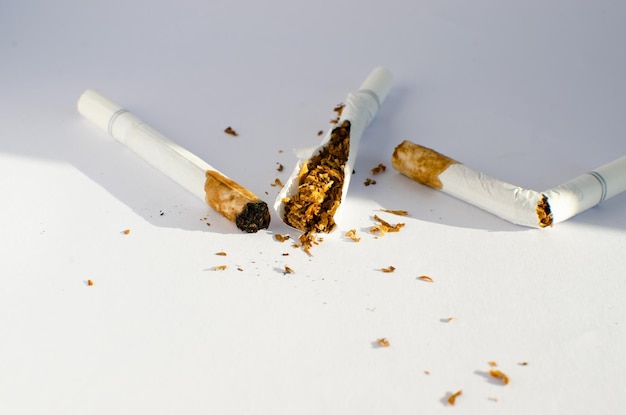 White cigarettes already smoked, no smoking and tobacco visible on white surface.