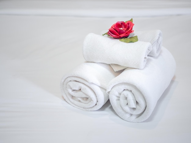 White clean towels decoration with red flower on white clean bed in hotel room