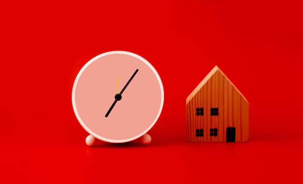 White clock and house not simulated on red background with copy space