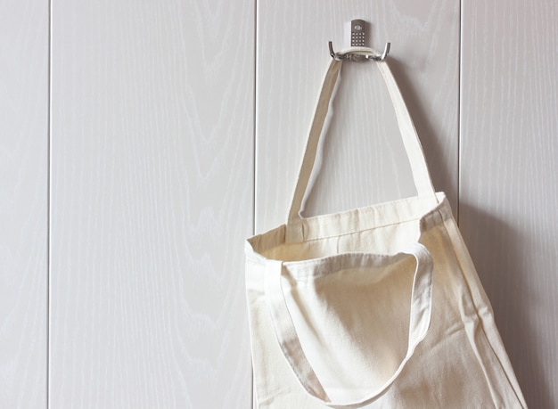 White cloth bag hangs on a hook on wooden wall