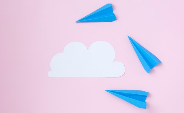 White cloud of paper and paper planes on a pink background