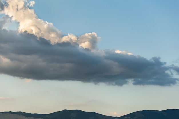 White clouds over the tops of the mountains against the blue sky