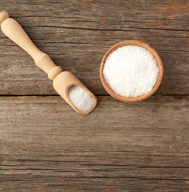 White coarse salt in a wooden spoon and woode bowl