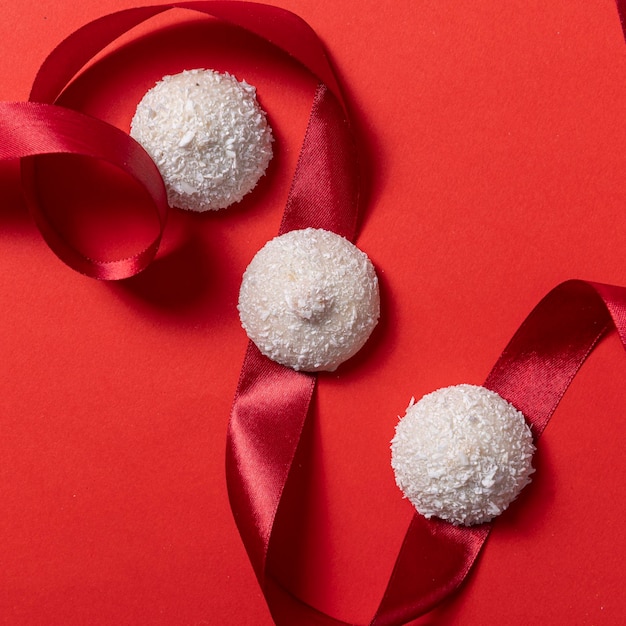 White coconut cookies on a red ribbon on a red background