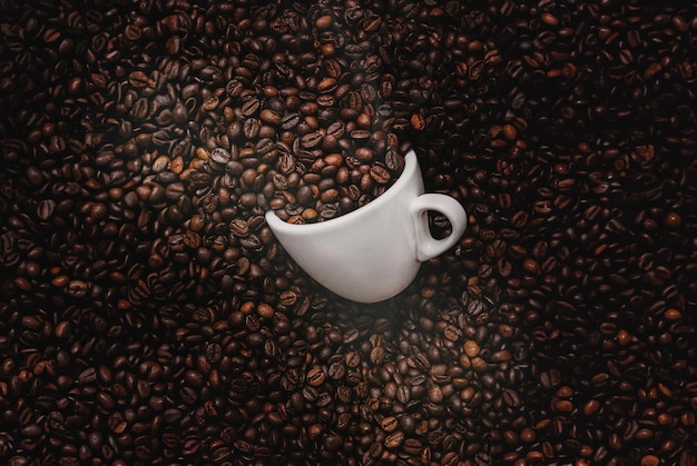 A white coffee cup among roasted coffee beans